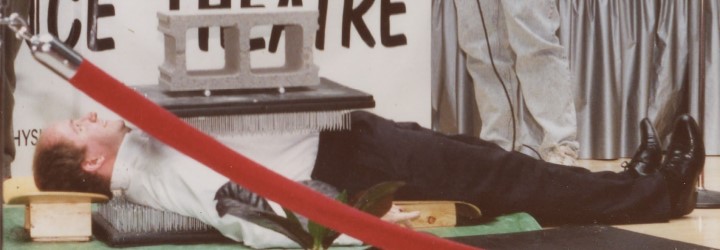 school principal laying horizontal on bed of nails on floor